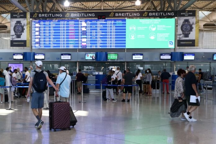 επιβατική κίνηση αεροδρομίων: επιβάτες στο check-in και πίνακες αναχωρήσεων με πολυσύχναστα δρομολόγια